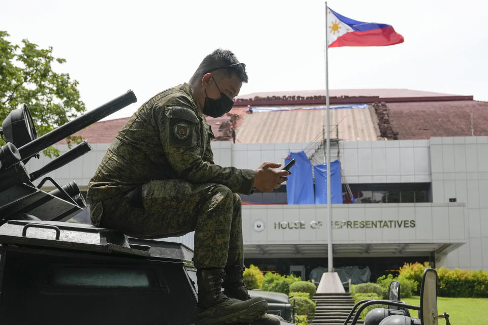 FILE - A soldier uses his smartphone on top of an armored personnel carrier as they secure the area where ballot boxes containing the Certificates of Canvass and Election Returns arrive at the House of Representatives in Quezon City, Philippines on May 23, 2022. The Philippine defense chief has ordered all defense personnel and the 163,000-member military to refrain from using online tech tools that use artificial intelligence to generate personal portraits, saying they could pose security risks. (AP Photo/Aaron Favila, File)