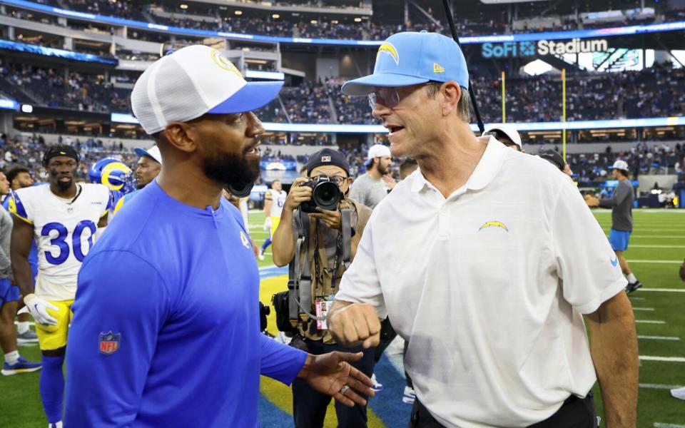 Rams defensive backs coach and passing game coordinator Aubrey Pleasant, left, greets Chargers coach Jim Harbaugh.