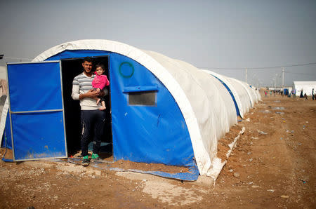 Displaced Iraqi Ahmed Yassin, 30, poses for a photograph with his daughter Malk, 2, at Hammam al-Alil camp south of Mosul, Iraq, March 29, 2017. Yassin, a taxi driver from East Mosul, said he is trying to keep his young child busy to forget the war. There is little to do but he takes her for tours around the camp to get her out of the tent where he lives with his wife, whom he married three years ago. The family got split when they escaped Mosul; he was arrested for security checks for two days. His wife and child arrived first in the camp, he joined them later. They have been in the camp for a month. REUTERS/Suhaib Salem