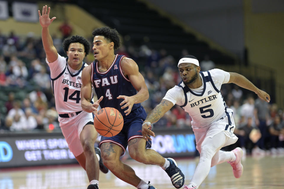 Florida Atlantic guard Bryan Greenlee (4) has the ball poked away by Butler guard Posh Alexander (5) as guard Landon Moore (14) helps defend during the first half of an NCAA college basketball game, Thursday, Nov. 23, 2023, in Kissimmee, Fla. (AP Photo/Phelan M. Ebenhack)