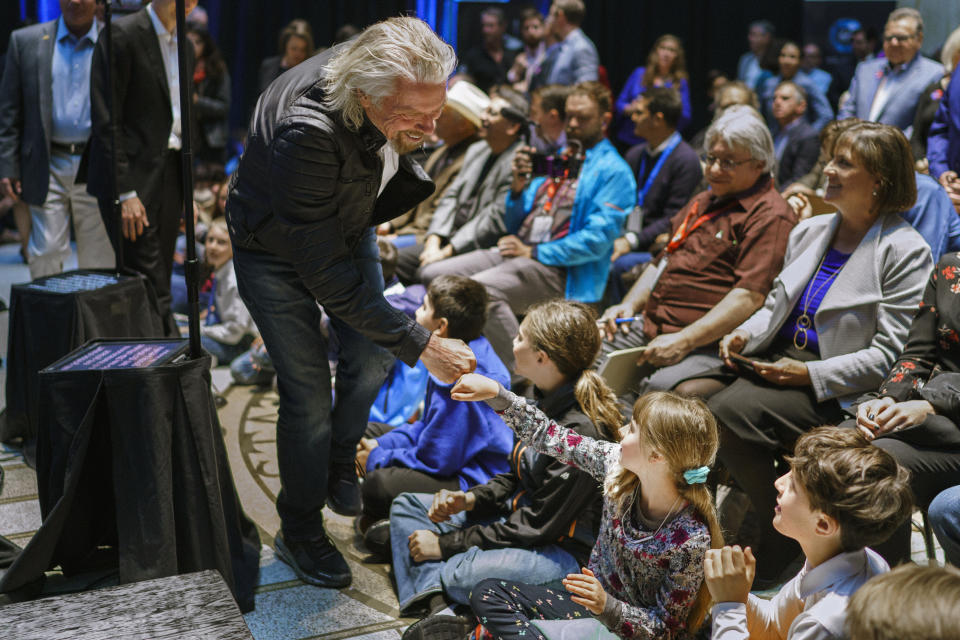Virgin Galactic founder Richard Branson, gives a fist bump to Sonia Thorp, 9, of Carlos Gilbert Elementary at the beginning of an event at the state capital on Friday, May 10, 2019, in Santa Fe, N.M. Branson announced Friday that his company will begin shifting operations from California to a spaceport and specialized runway in the New Mexico desert in final preparations for commercial flights. (AP Photo/Craig Fritz)