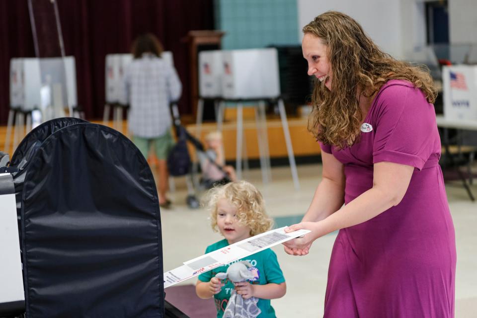 Clark Pittman, 3, watches his mother, Katherine Pittman, both of Pittsfield Township, insert her ballot into the tabulator for the primary election at Carpenter Elementary in Pittsfield Township on Tuesday, Aug. 2, 2022. Most Michigan counties transmit unofficial election results by uploading them from memory cards attached to the tabulator.