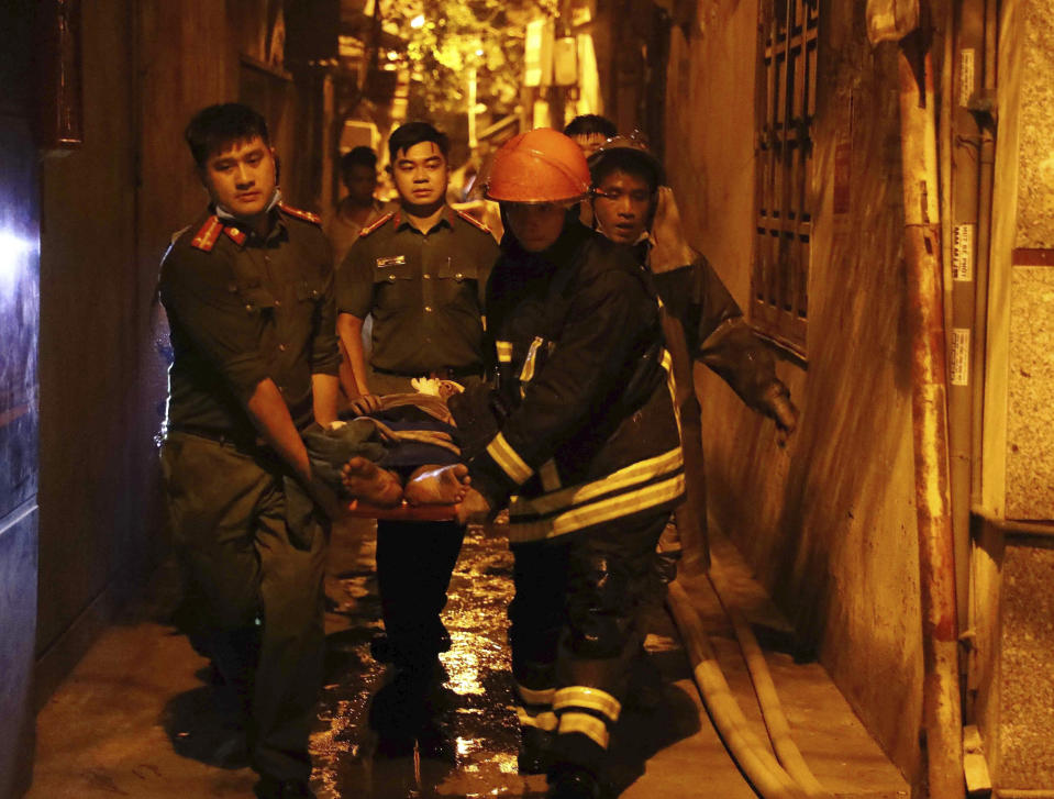 Rescue workers carry a person on stretcher out of a building on fire in Hanoi, Vietnam Wednesday, Sept. 13, 2023. Authorities said "many" people had been killed after a fire broke out in the apartment block. (Pham Trung Kien/ VNA via AP)