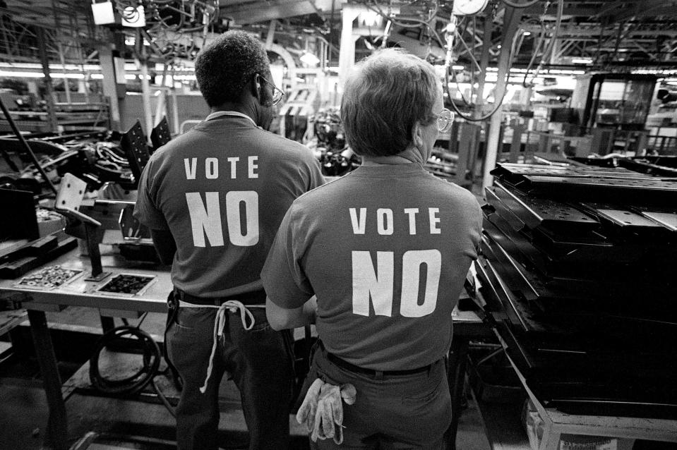 Two Nissan workers, showing that they are not endorsing the United Auto Workers union, are working on the line at the plant in Smyrna, Tenn., on July 26, 1989. Technicians sporting either "Vote No" or "Vote Yes" T-shirts and buttons worked side by side before and after casting votes on representation by the UAW union.