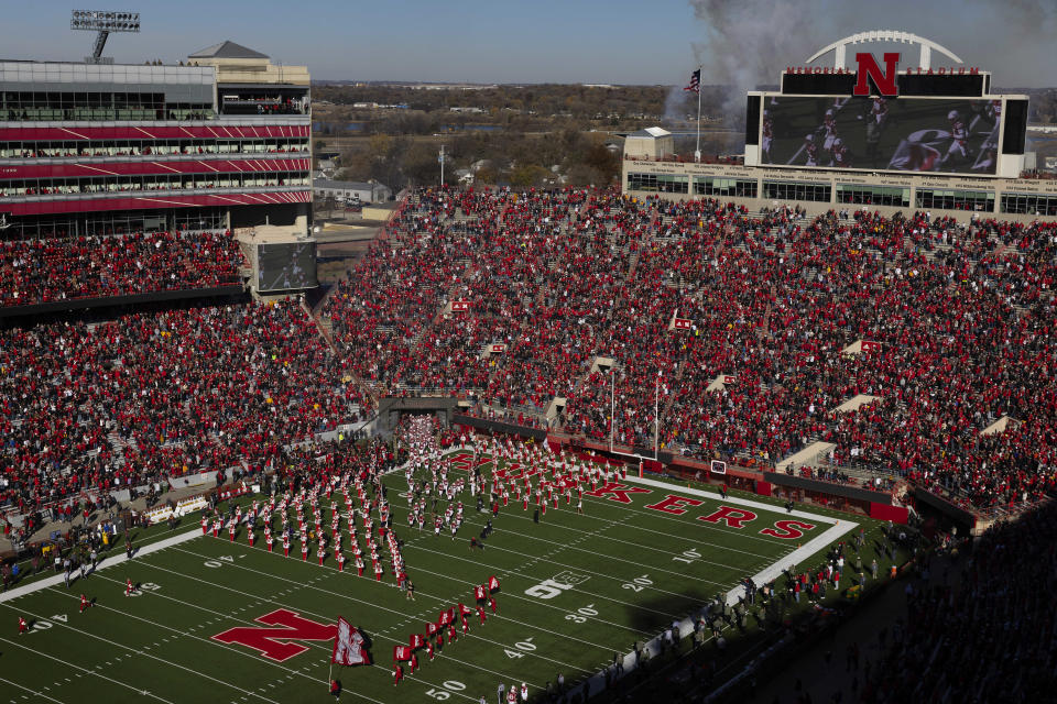 The Nebraska football team enters the field as the marching band and cheerleaders perform before playing against Minnesota in an NCAA college football game at Memorial Stadium on Saturday, Nov. 5, 2022, in Lincoln, Neb. College athletic programs of all sizes are reacting to inflation the same way as everyone else. They're looking for ways to save. (AP Photo/Rebecca S. Gratz)