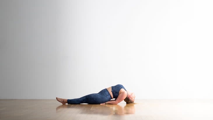Woman in blue tights and crop top practices Matsyasana, Fish Pose