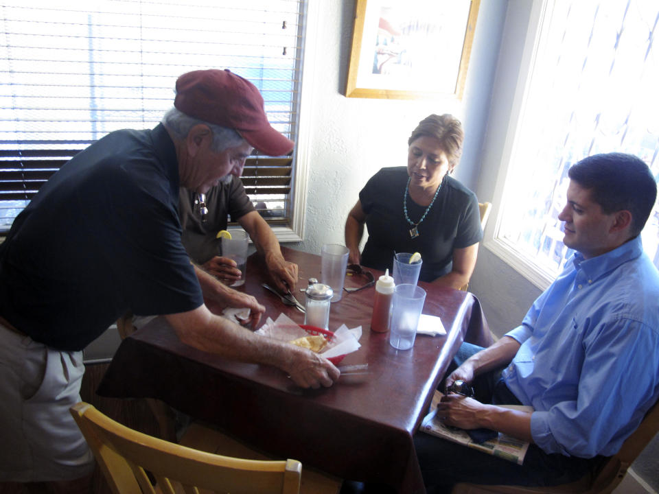 In this Sept 5, 2013 photo, El Patio de Albuquerque owner David Sandoval, left, brings customers sopapillas, a local New Mexican dish. El Patio is a longtime, unpretentious eatery near Albuquerque’s University of New Mexico campus. For nearly four decades, multi-generational families, tourists, professors, students _ even celebrities _ have lined up outside this former house for robust but simple fare. (AP Photo/Russell Contreras)