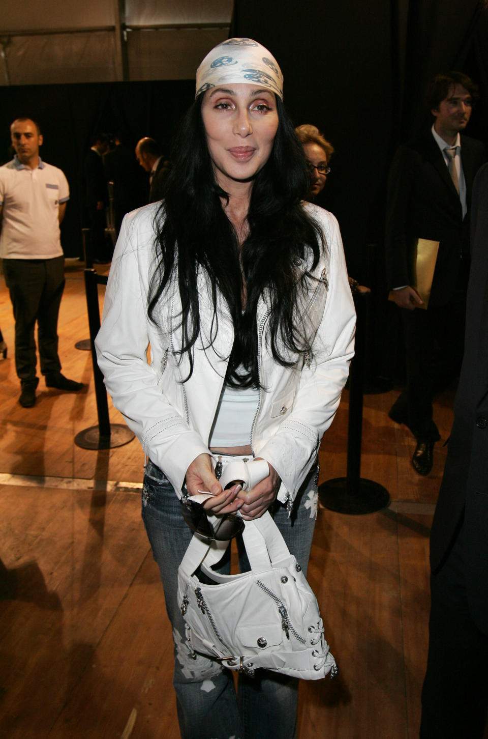 Cher in a wide headband, jeans, and a short jacket