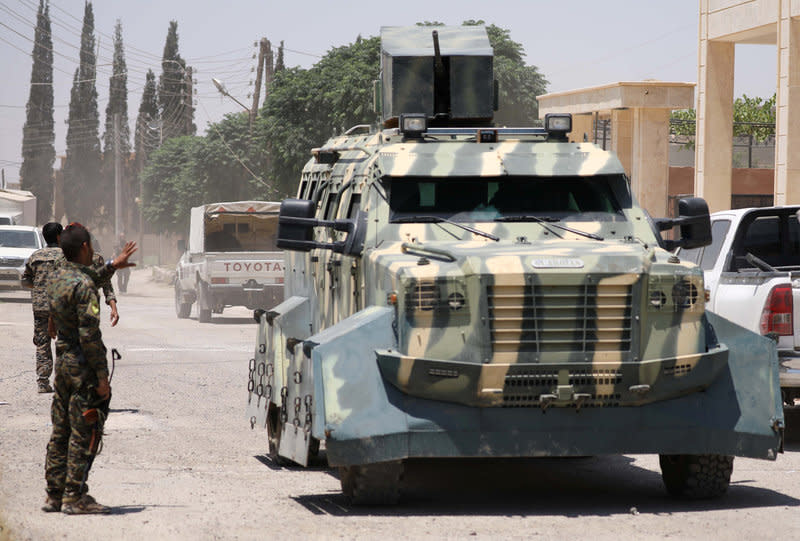 A Syrian Democratic Forces (SDF) fighter gestures towards an armoured vehicle in Hawi Hawa village, west of Raqqa, Syria June 11, 2017. REUTERS/Rodi Said