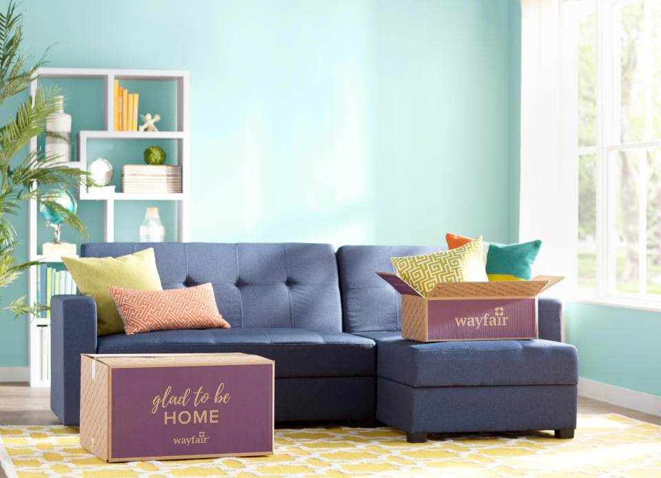 A living room with Wayfair boxes on the floor and couch.