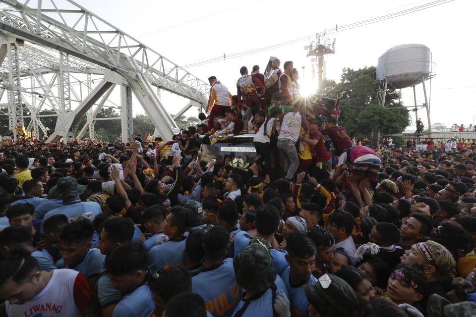 A crowd of Filipino Roman Catholic devotees follow the carriage of the Black Nazarene as it enters Ayala bridge during a raucous procession to celebrate its feast day Thursday, Jan. 9, 2020, in Manila, Philippines. A mammoth crowd of mostly barefoot Filipino Catholics prayed for peace in the increasingly volatile Middle East at the start Thursday of an annual procession of a centuries-old black statue of Jesus Christ in one of Asia's biggest religious events. (AP Photo/Aaron Favila)