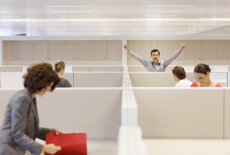 A man cheers in a cubicle.