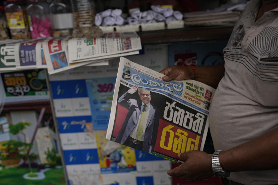 A man holds a newspaper with news of Ranil Wickremesinghe's election in Colombo, Sri Lanka, Thursday, July 21, 2022. Sri Lanka's prime minister was elected president Wednesday by lawmakers who opted for a seasoned, veteran leader to lead the country out of economic collapse, despite widespread public opposition. (AP Photo/Rafiq Maqbool)