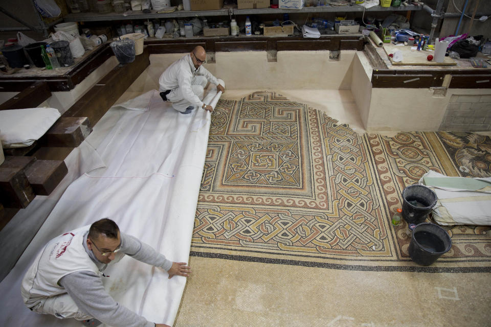 In this Thursday, Dec. 6, 2018 photo, restoration experts work on a mosaic inside the Church of the Nativity, built atop the site where Christians believe Jesus Christ was born, in the West Bank City of Bethlehem. The renovation is lifting spirits in the biblical town of Bethlehem ahead of Christmas, offering visitors a look at ancient mosaics and columns that have been restored to their original glory for the first time in 600 years. (AP Photo/Majdi Mohammed)