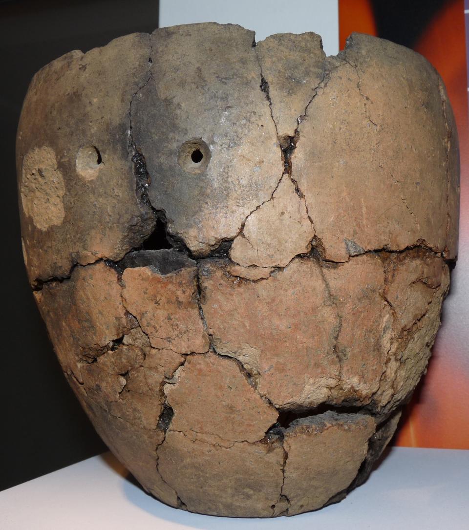 a table-sized urn with a bunch of cracks in it, pieced together into shape and sitting on a table