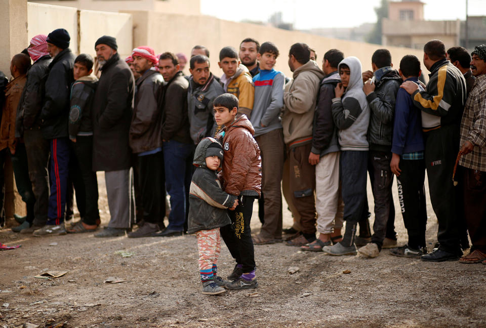 An Iraqi boy holds the hand of his sister in the at Zahra district