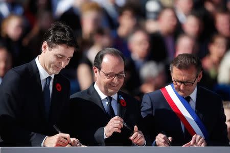 From L-R, Canadian Prime Minister Justin Trudeau, French President President Francois Hollande and Frederic Leturque, Mayor of Arras, sign poppies at Heroes Square in Arras, France, as part of a ceremony to commemorate the 100th anniversary of the Battle of Vimy RIdge April 9, 2017. REUTERS/Christian Hartmann