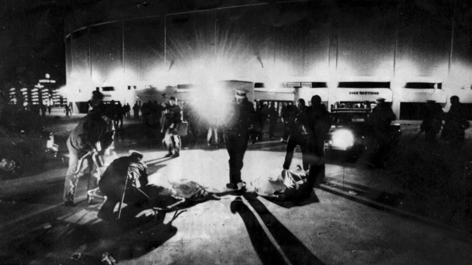 FILE - Cincinnati Police and rescue workers attend to two bodies of people crushed to death outside the fateful The Who concert at Riverfront Coliseum in Cincinnati, Ohio, Dec. 3, 1979. (Ed Reinke/The Cincinnati Enquirer via AP, File)
