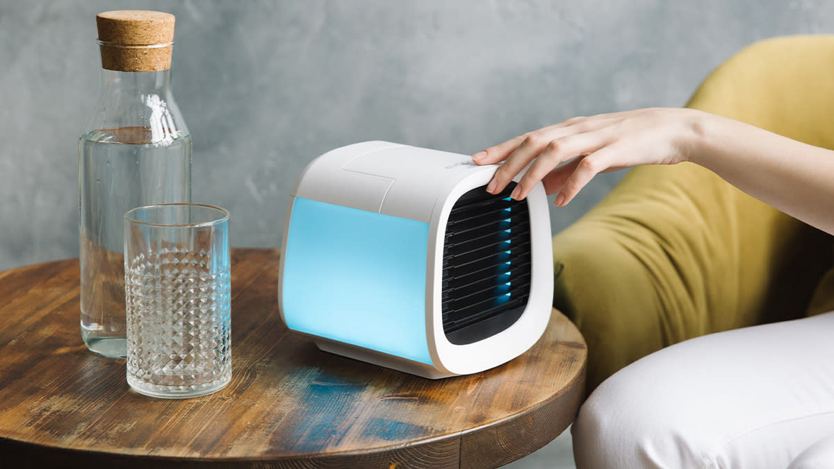 A hand on a personal air conditioner on a table