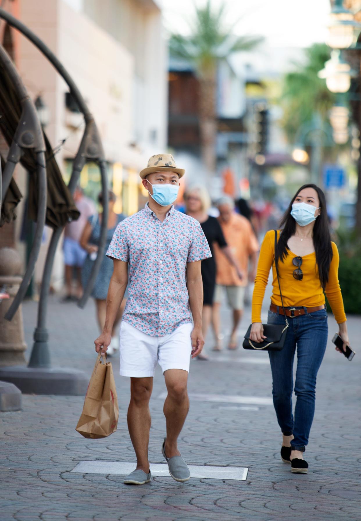 People don masks while walking along Palm Canyon Drive in Palm Springs over the weekend. Health officials ordered bars shut down again, effective Tuesday, as cases of coronavirus spiked.