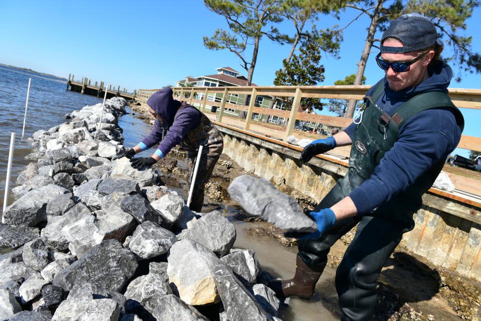 Brennan Wehrhahn and Rachel Gwin with the Choctawhatchee Basin Alliance assemble a limestone breakwater at Liza Jackson Park. When completed, the breakwater will cover most of the park's waterfront.