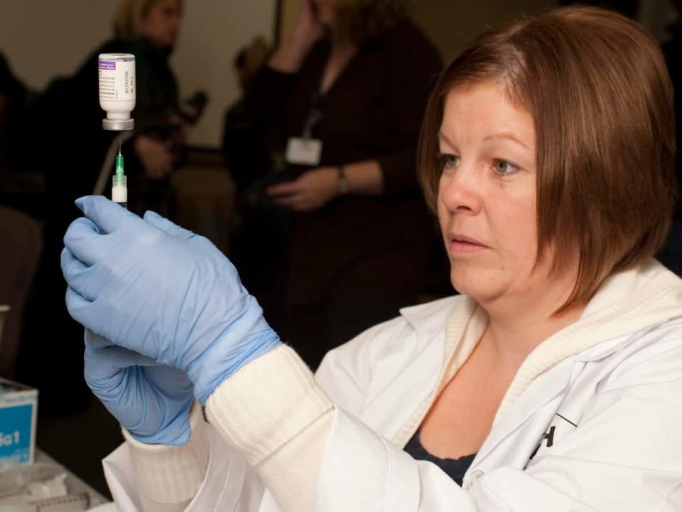 Licensed nurse practitioner Christine Melanson prepares doses of the H1N1 influenza vaccine at the Dr. Everett Chalmers Hospital in Fredericton, N.B. in 2009. The 2009 H1N1 pandemic continues to affect how younger ones do with flu, doctors say. (David Smith/The Canadian Press - image credit)