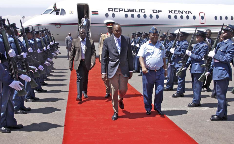 In this photo released by the Kenya Presidency, Kenyan President Uhuru Kenyatta, center, and Deputy President William Ruto, center-left, are welcomed back by Chief of the Defence Forces Staff Gen. Julius Karangi, center-right, after attending the African Union (AU) summit in Addis Ababa, at the airport in Nairobi, Kenya Saturday, Feb. 1, 2014. The African Union urged its members to "speak with one voice" against criminal proceedings at the International Criminal Court against sitting presidents, according to a statement Saturday, saying it was disappointed that a request to the U.N. Security Council to defer the trials of Kenya's leaders "has not yielded the positive result expected." (AP Photo/Kenya Presidency)