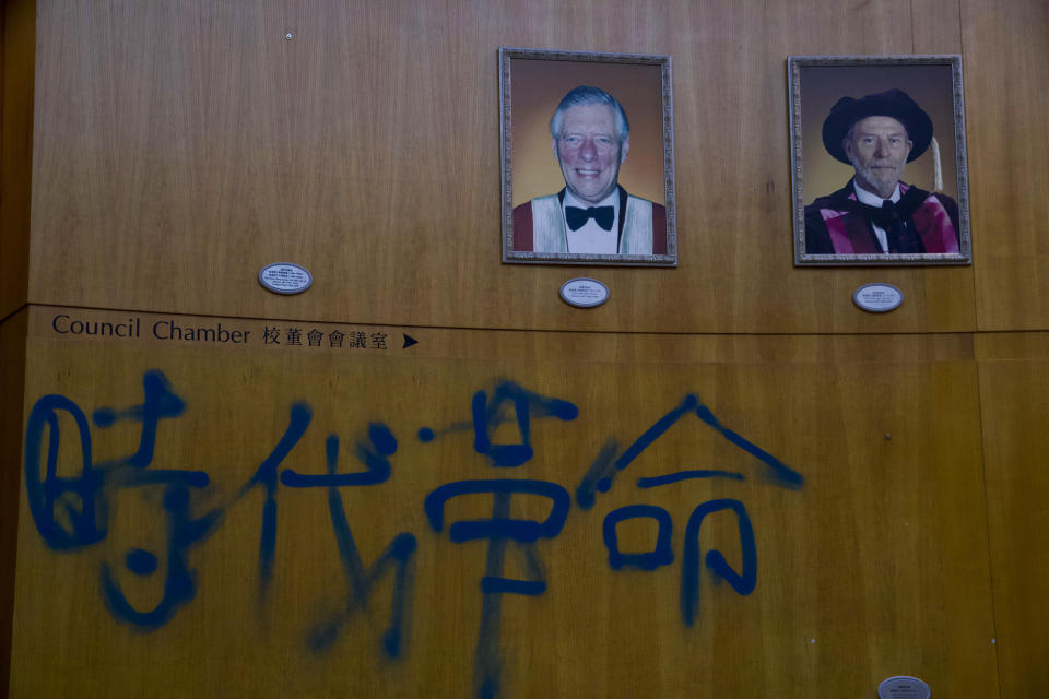 Portraits of former university council chairpersons hang on the wall displaying the the words "Era Revolution" sprayed by protesters at Polytechnic University in Hong Kong, Tuesday, Nov. 26, 2019. Hong Kong's embattled leader Carrie Lam refused to offer any concessions to anti-government protesters despite a local election trouncing, saying Tuesday that she will instead accelerate dialogue and identify ways to address societal grievances. (AP Photo/Ng Han Guan)