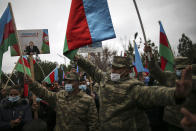 Azerbaijani soldiers hold national flags and a portrait of Azerbaijani President Ilham Aliyev as they celebrate the transfer of the Lachin region to Azerbaijan's control, as part of a peace deal that required Armenian forces to cede the Azerbaijani territories they held outside Nagorno-Karabakh, in Aghjabadi, Azerbaijan, Tuesday, Dec. 1, 2020. Azerbaijan has completed the return of territory ceded by Armenia under a Russia-brokered peace deal that ended six weeks of fierce fighting over Nagorno-Karabakh. Azerbaijani President Ilham Aliyev hailed the restoration of control over the Lachin region and other territories as a historic achievement. (AP Photo/Emrah Gurel