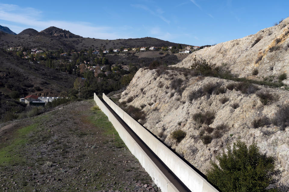 An emergency spillway for the Las Virgenes Municipal Water District's reservoir stretches along the hillside in Westlake Village, Calif., Wednesday, Jan. 5, 2022. The Las Virgenes Municipal Water District's approach is one example of how water districts are pushing Californians to save as the drought continues despite a wet start to winter. Las Virgenes is installing a new metering system that gives people a real-time look at their water use. It's also lowering the threshold for penalizing wasters and threatening to restrict the flow of water for households that don't get their water use back under control. (AP Photo/Jae C. Hong)