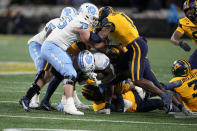 North Carolina running back British Brooks is tackled by West Virginia during the first half of an NCAA college football game at the Duke's Mayo Bowl Wednesday, Dec. 27, 2023, in Charlotte, N.C. (AP Photo/Chris Carlson)