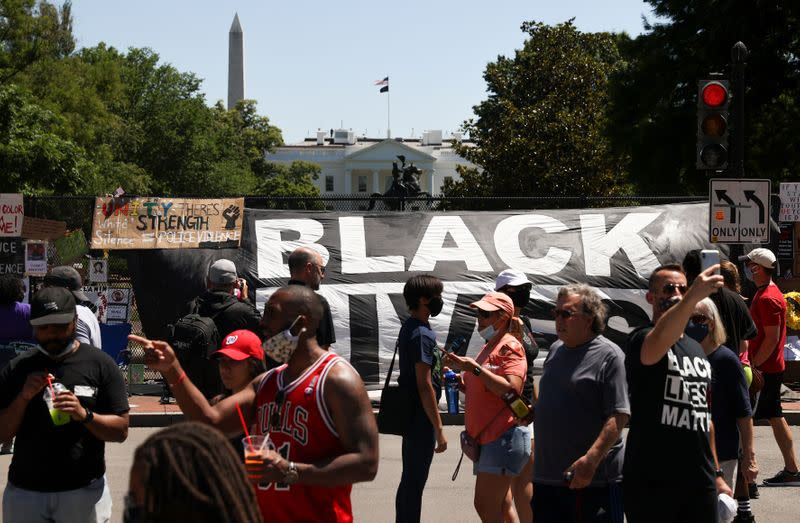 People gather to view protest signs now affixed to the fence around Lafayette Square at the scene where protesters clashed with police near the White House in Washington