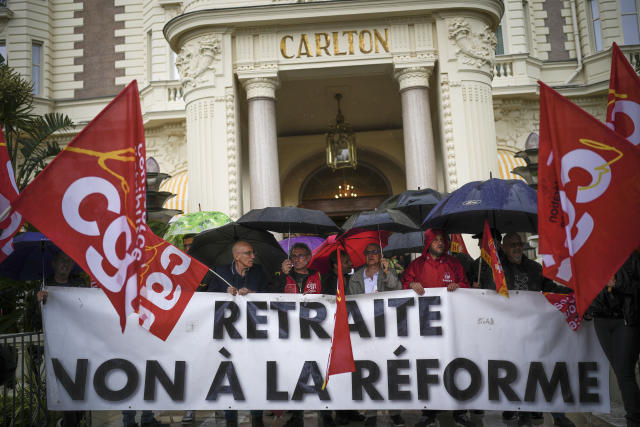 Hotel workers protest pension reforms outside of the Carlton hotel with a banner that says 'Retirement No to the Reform' during the 76th international film festival, Cannes, southern France, Friday, May 19, 2023. (AP Photo/Daniel Cole)