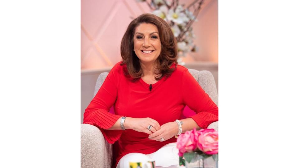 Jane McDonald in a red jumper and white trousers