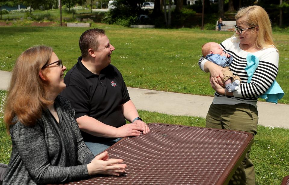 "Ferry Godmother" Tara Kenneway, right, holds Charlie Wetzel while visiting with his parents Leanne and Pete Wetzel at Bainbridge Island's Waterfront Park on May 19.