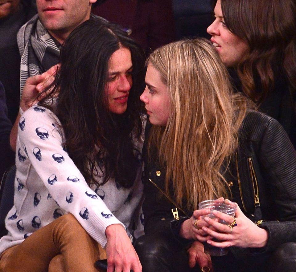 michelle rodriguez and cara delevingne looking at each other at basketball game
