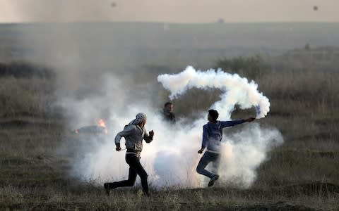 Palestinian protesters throw back a teargas canister fired by Israeli troops during clashes on the Israeli border with Gaza, Saturday, Dec. 9, 2017. - Credit: AP