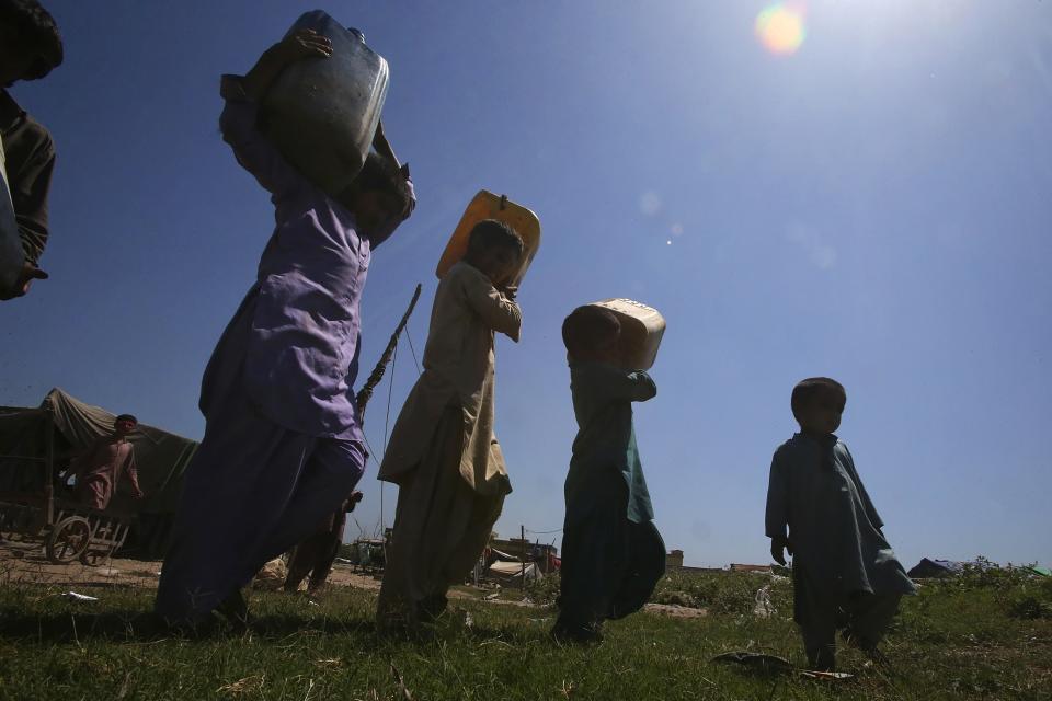 Kids hold canisters to get drinking water from a nearby supply line on the outskirts of Peshawar, Pakistan, Wednesday, May 10, 2023. The flooding in Pakistan killed at least 1,700 people, destroyed millions of homes, wiped out swathes of farmland, and caused billions of dollars in economic losses. In Khyber Pakhtunkhwa, residents had to rely on contaminated water, so now authorities are taking steps to prepare for the next disaster. (AP Photo/Muhammad Sajjad)