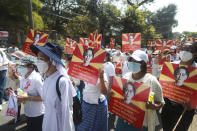 Anti-coup protesters hold posters with an image of deposed Myanmar leader Aung San Suu Kyi as they gather outside the U.N. Information Office in Yangon, Myanmar, Sunday, Feb. 14, 2021. Vast numbers of people all over Myanmar have flouted orders against demonstrations to march again in protest against the military takeover that ousted the elected government of Suu Kyi. (AP Photo)