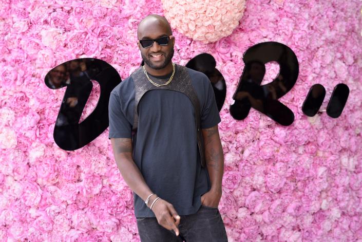 Virgil Abloh posing in front of a display of pink flowers.