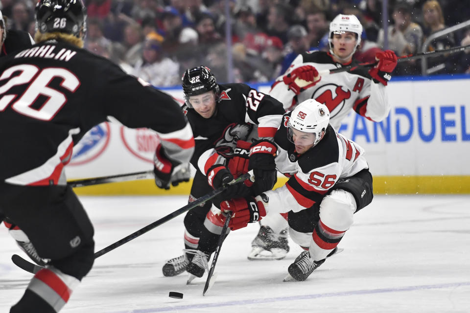 Buffalo Sabres right wing Jack Quinn (22) reaches for the puck against New Jersey Devils left wing Erik Haula (56) during the first period of an NHL hockey game in Buffalo, N.Y., Friday, March 24, 2023. (AP Photo/Adrian Kraus)