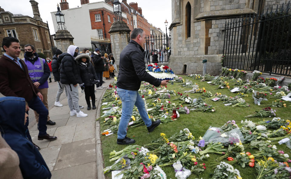 A man prepares to lay a flower wreath outside the gates of Windsor Castle, a day after the death of Britain's Prince Philip, in Windsor, England, Saturday, April 10, 2021. Britain's Prince Philip, the irascible and tough-minded husband of Queen Elizabeth II who spent more than seven decades supporting his wife in a role that mostly defined his life, died on Friday. (AP Photo/Frank Augstein)