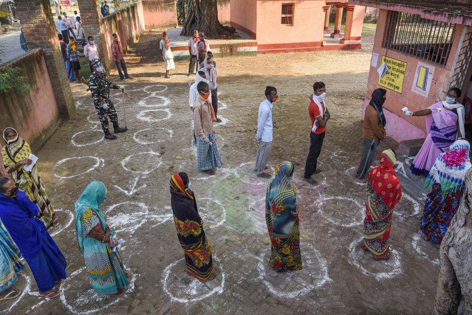 Voters, adhering to social distancing norms, stand in queues outside a polling station to cast their votes for the first phase of Bihar Assembly Elections, at Paligang constituency in Patna, Wednesday, 28 October.