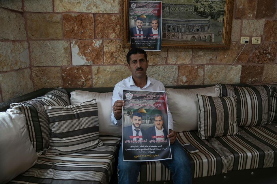 Abdelazim Wadi holds up a poster commemorating his brother, Ibrahim Wadi, and his nephew, Ahmed Wadi, who were killed by Israeli settlers during a funeral procession on Oct. 12, in the rural Palestinian village of Qusra, West Bank.