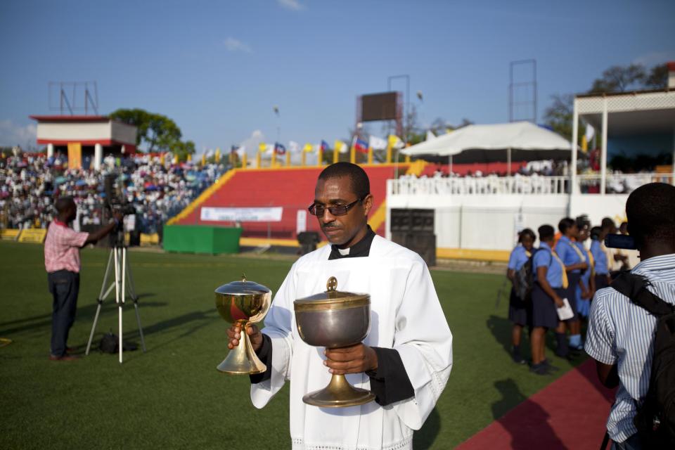 A priest carries chalices during a Mass lead by Cardinal Chibly Langlois at the national stadium Sylvio Cator in Port-au-Prince, Haiti, Sunday, March 9, 2014. Haiti's new Roman Catholic Cardinal Chibly Langlois celebrated his first Mass, telling an audience of several thousand people there is a need to show compassion for others. (AP Photo/Dieu Nalio Chery)