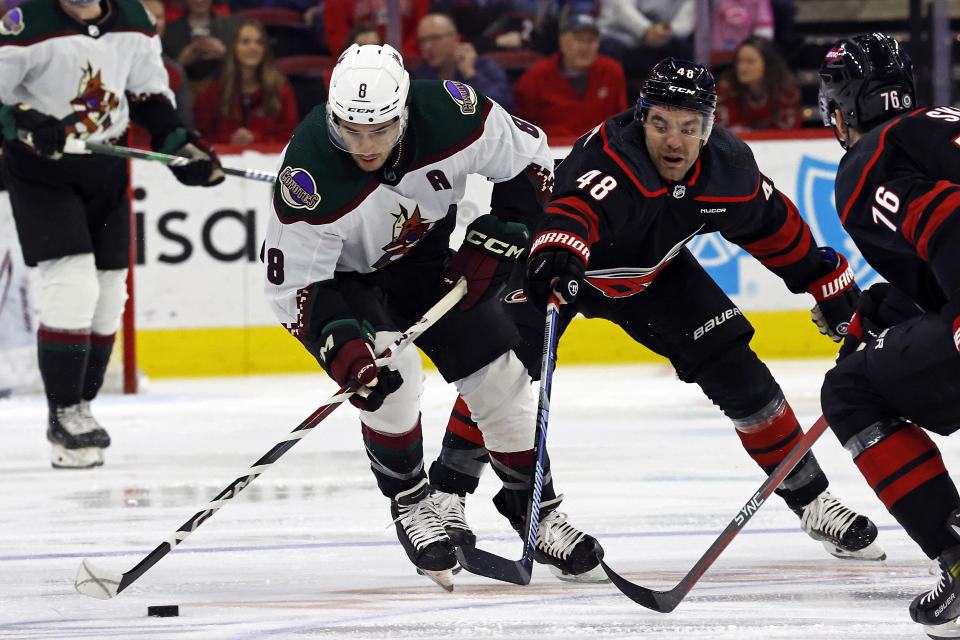 Arizona Coyotes' Nick Schmaltz (8) controls the puck next to Carolina Hurricanes' Jordan Martinook (48) during the first period of an NHL hockey game in Raleigh, N.C., Saturday, Jan. 27, 2024. (AP Photo/Karl B DeBlaker)