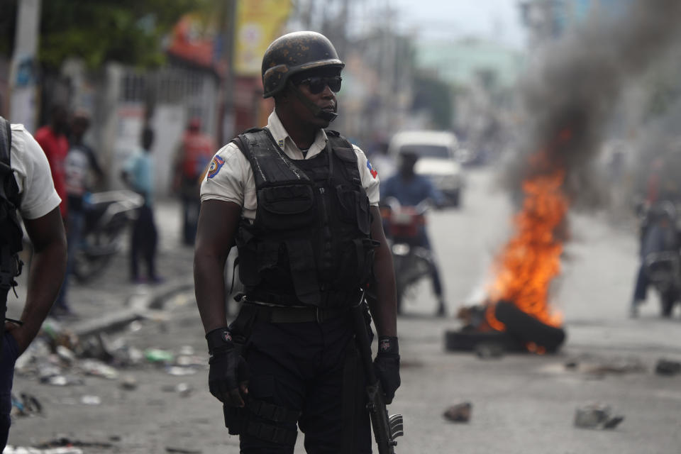 A police stands near a burning barricade set up by protesters in Port-au-Prince, Haiti, Monday, Sept. 30, 2019. Opposition leaders are calling for a nationwide push Monday to block streets and paralyze Haiti's economy as they press for Moise to give up power, and tens of thousands of their young supporters were expected to heed the call. (AP Photo/Rebecca Blackwell)