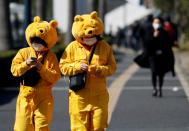 Visitors wearing protective face masks and Winnie the Pooh costumes, following an outbreak of the coronavirus, are seen outside Tokyo Disneyland in Urayasu