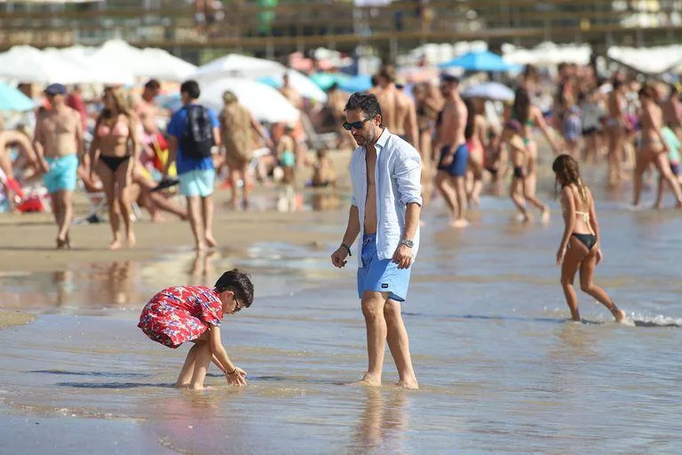 Siempre protegidos del sol, los más pequeños y sus padres se refrescaron con helados de agua y jugaron a la orilla del mar