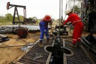 Men work at an oil pump in Lagunillas, Ciudad Ojeda, in the state of Zulia, Venezuela, March 18, 2015. REUTERS/Isaac Urrutia